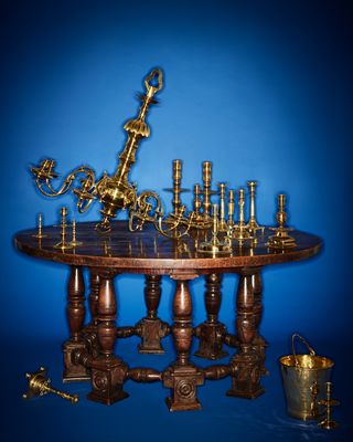 Rockefeller collection A selection of European brass candlesticks and a brass chandelier atop an Italian walnut table