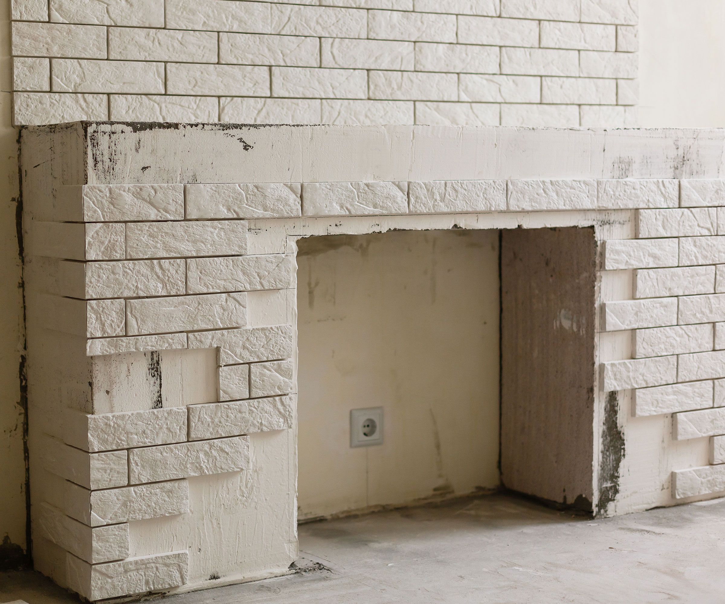 old disused fireplace with stick on white brick cladding