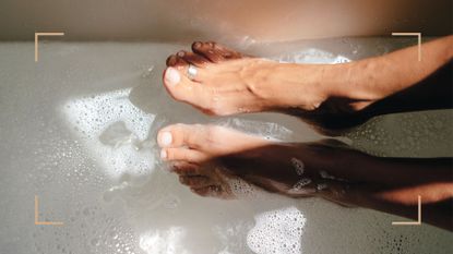 a womans feet over a bubbly footbatj to illustrate how often should you get a pedicure 