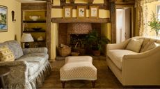 yellow painted country heritage style traditional living room with wooden ceiling beams and vintage furniture 