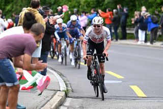 Marc Hirschi attacking up a climb with fans clapping him on