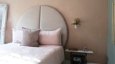 Statement headboard against a pale pink wall with wall lights and pink linen bedding