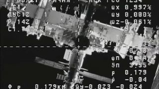 a black and white image of a space station overlayed with data and a crosshair as seen from a navigation camera aboard a cargo spacecraft