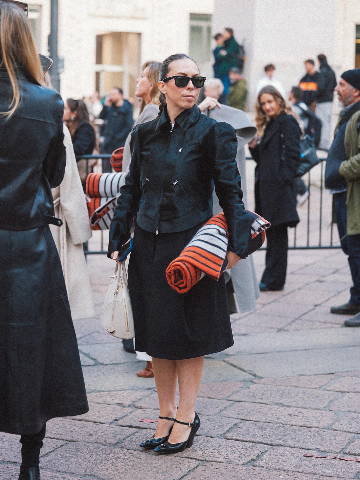 woman posing on the street wearing a jacket, dress, and heels