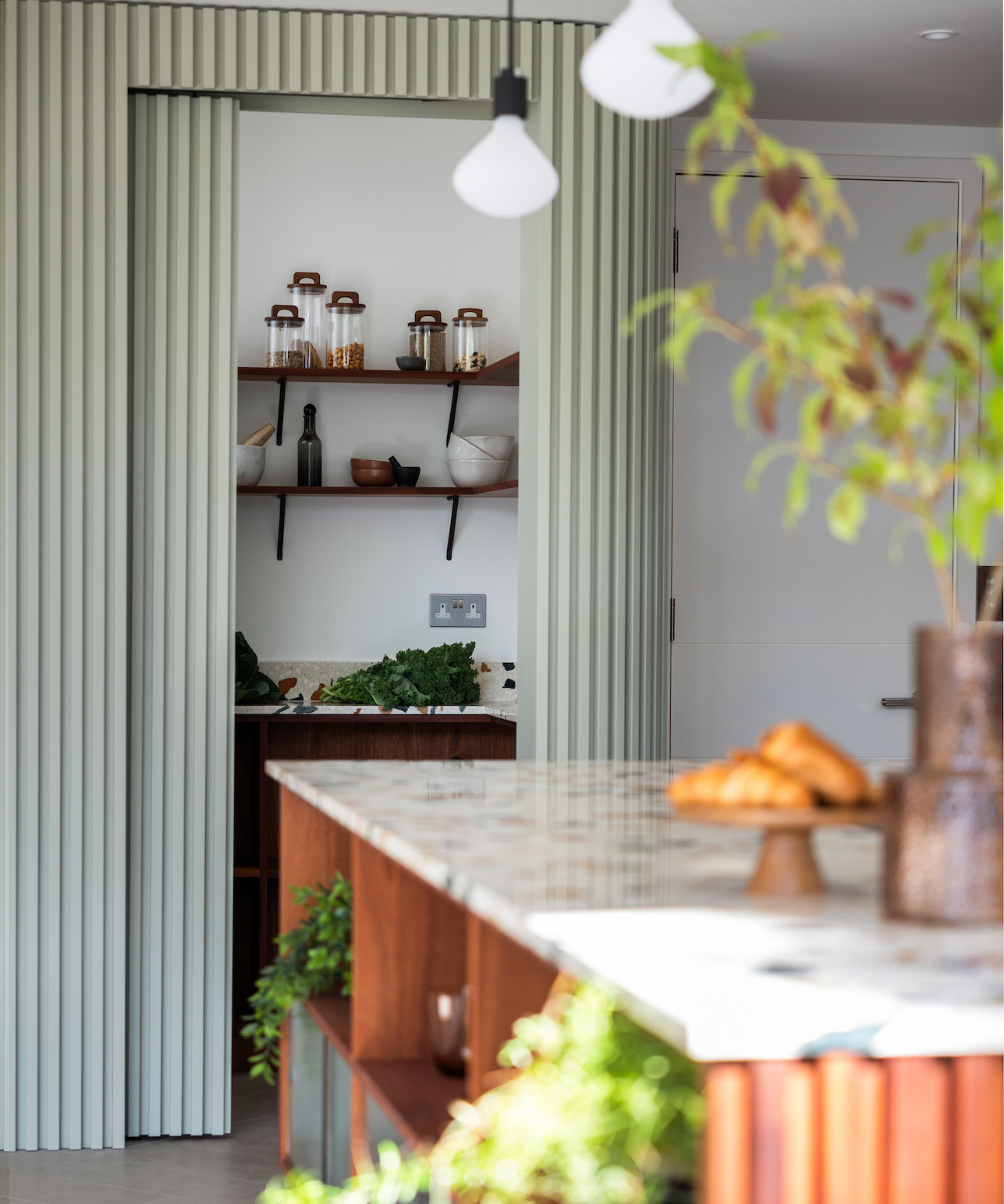 hidden pantry behind fluted green sliding curved door