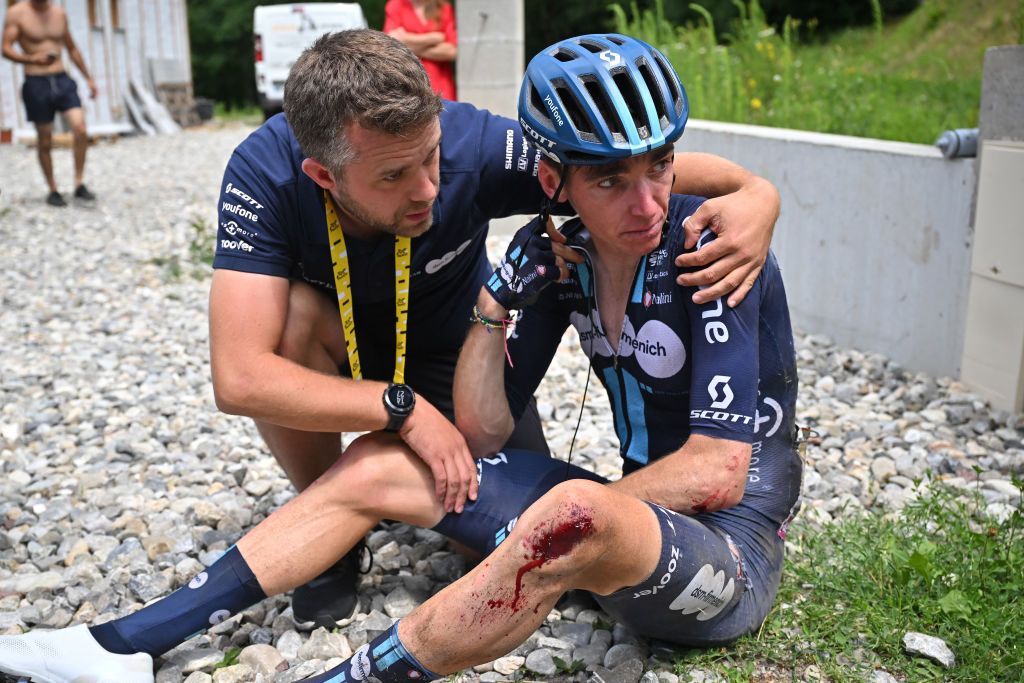 Team DSM - Firmenich's French rider Romain Bardet is assisted by a team member after crashing during the 14th stage of the 110th edition of the Tour de France cycling race, 152 km between Annemasse and Morzine Les Portes du Soleil, in the French Alps, on July 15, 2023. (Photo by Marco BERTORELLO / AFP)