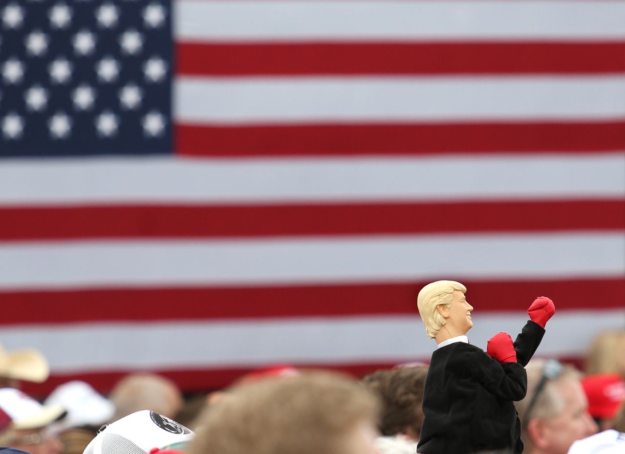 A Trump supporter holds up a boxing doll that looks like him. 