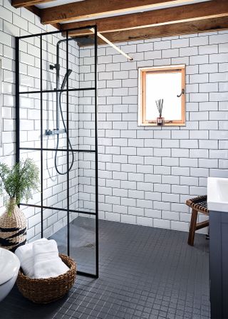 bathroom with black floor, white metro tiles andshower and black framed crittal screen