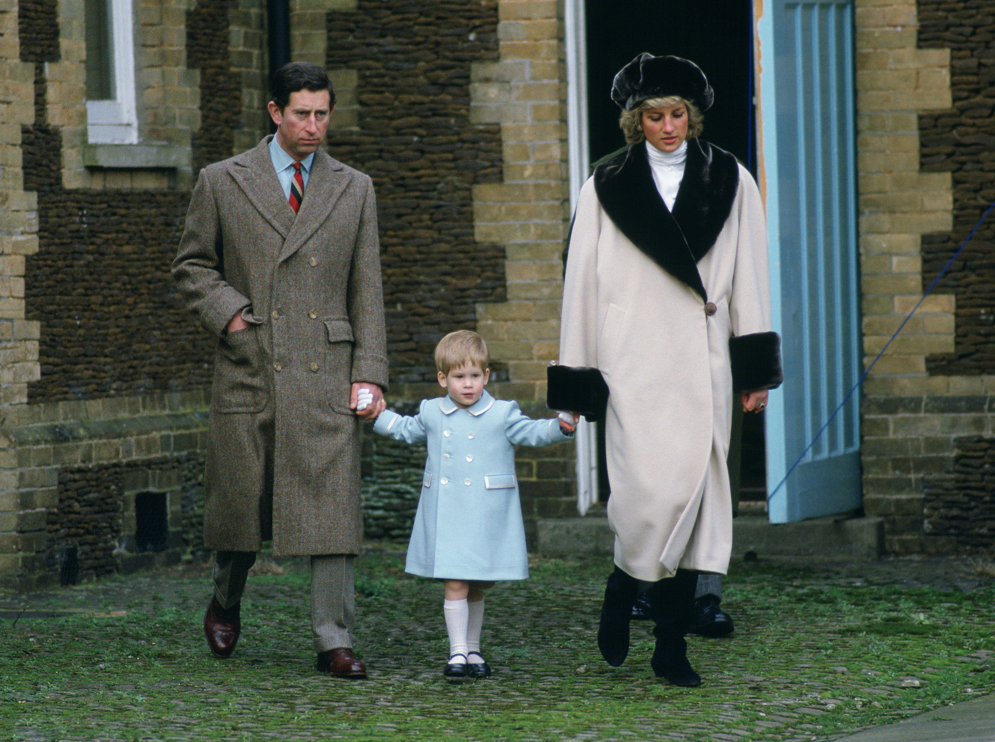 King Charles, Prince Harry and Princess Diana wearing winter coats and holding hands