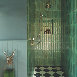 A shower tiled in rich dark green rectangular tiles