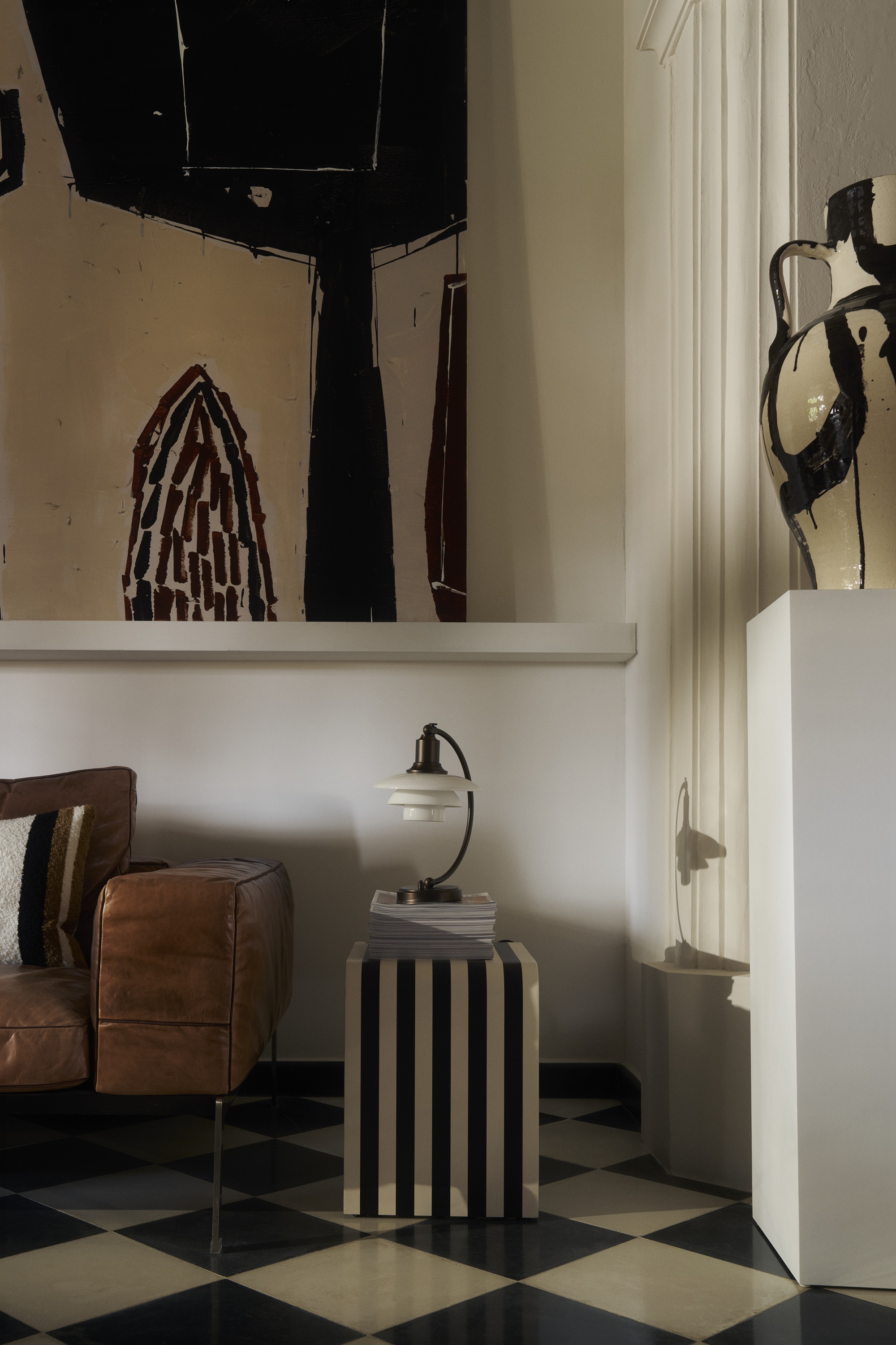 a striped side table with a lamp in a modern home with a monochromatic color palette