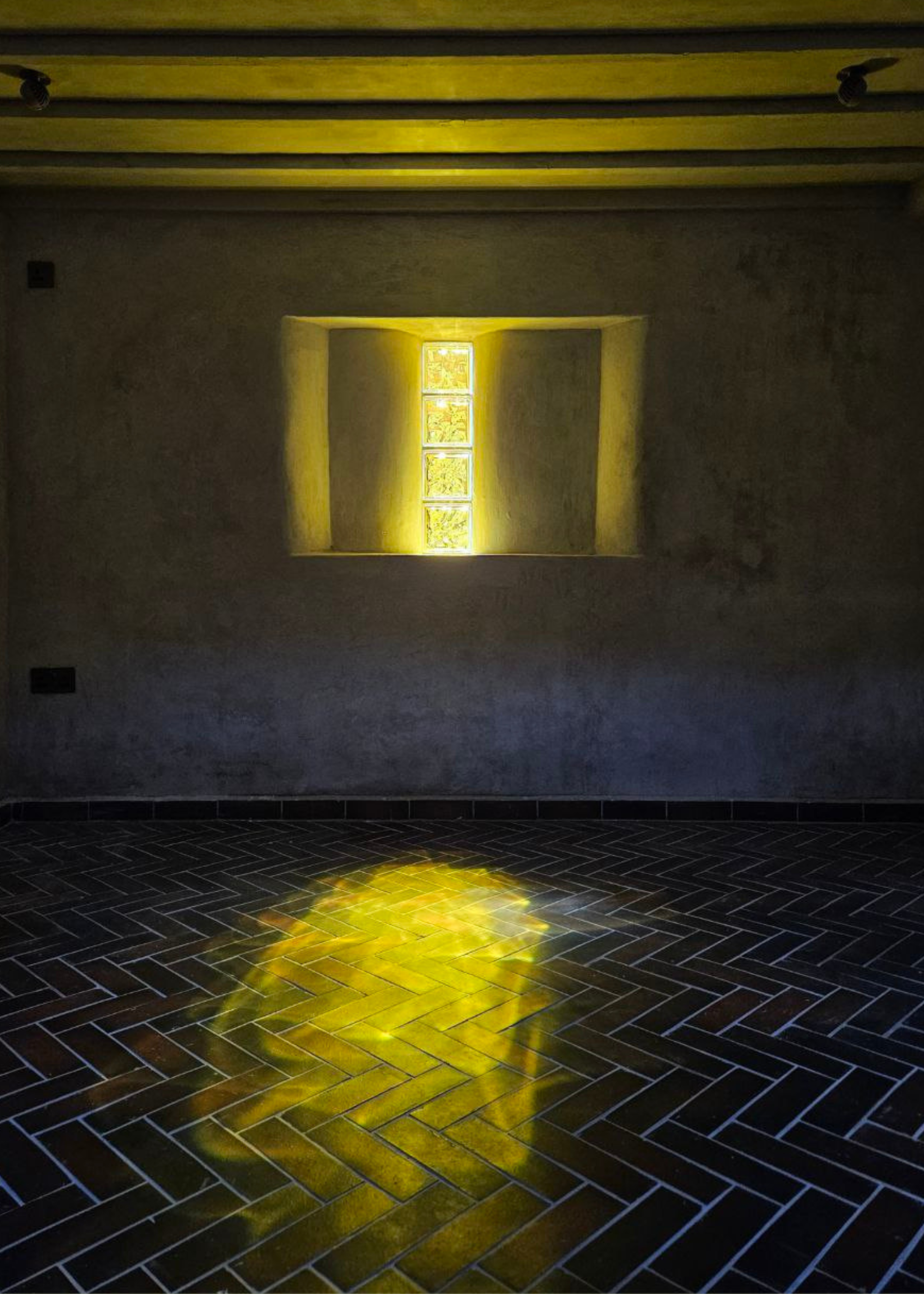 A room with sunlight reflecting on the tiled floor through glass blocks
