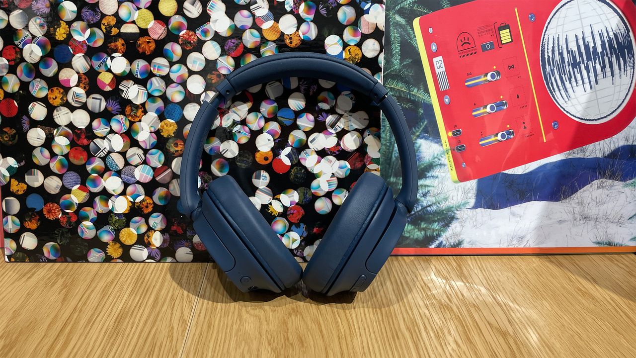 A blue pair of Sony WH-CH720N over-ear headphones propped up against a colourful backdrop.