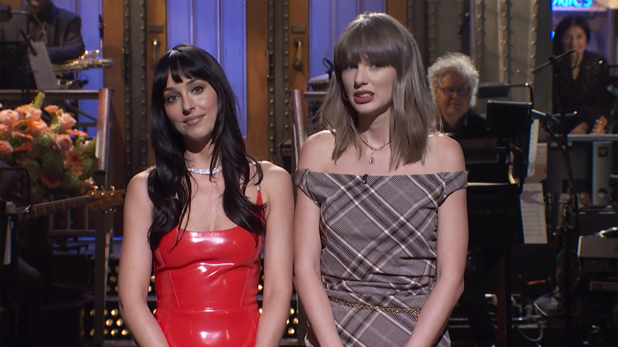 Dakota Johnson in red latex and Taylor swift in plaid on SNL stage during monologue October 2026.