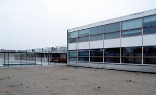 Exterior of grey and white two-storey school building with courtyard area.