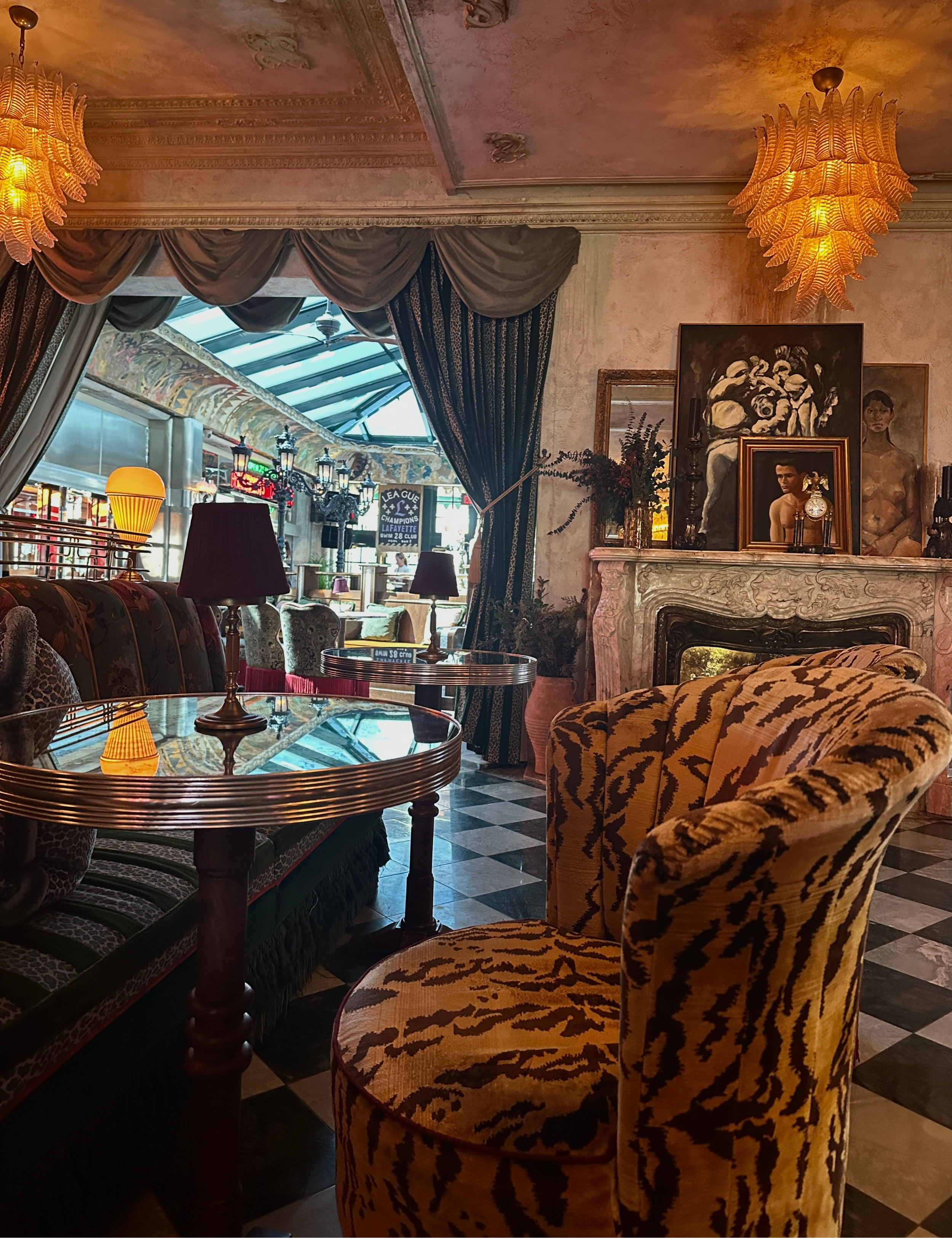 Lafayette Hotel lobby featuring opulent multi-tiered lighting, lacquered bistro tables, and tiger print upholstered chairs.