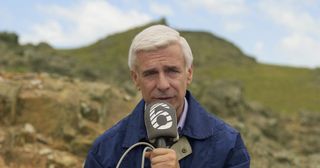 A man with a microphone standing in the mountains