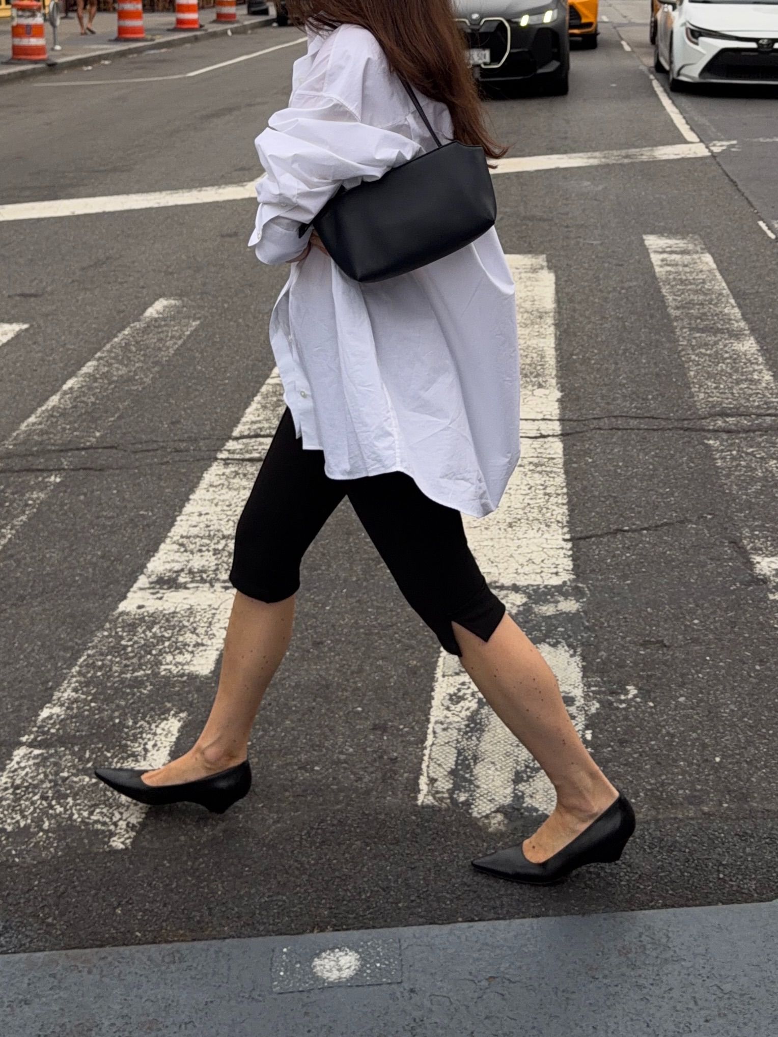 An image of an influencer wearing a white button-down shirt with black capris and black micro wedge heels, one of autumn 2026's shoe trends