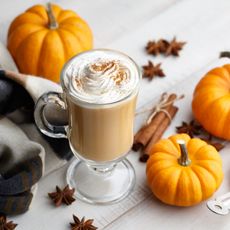 Pumpkin spice latte next to decorative pumpkins