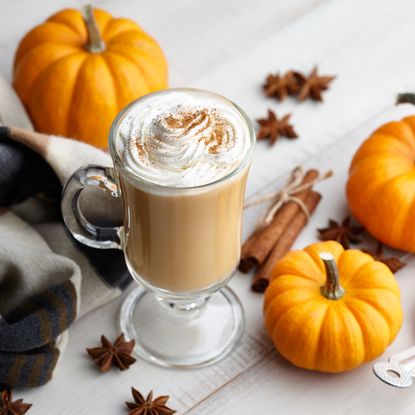 Pumpkin spice latte next to decorative pumpkins