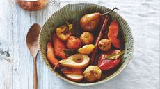 Bowl of baked fall fruits with a wooden spoon set next to it