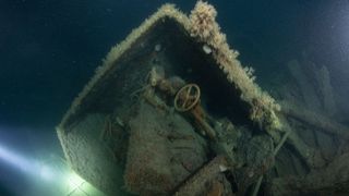 An underwater photo of a shipwreck with sea life growing along it