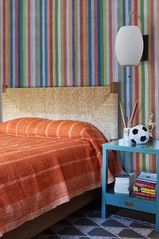 bedroom with striped wallpaper behind the bed