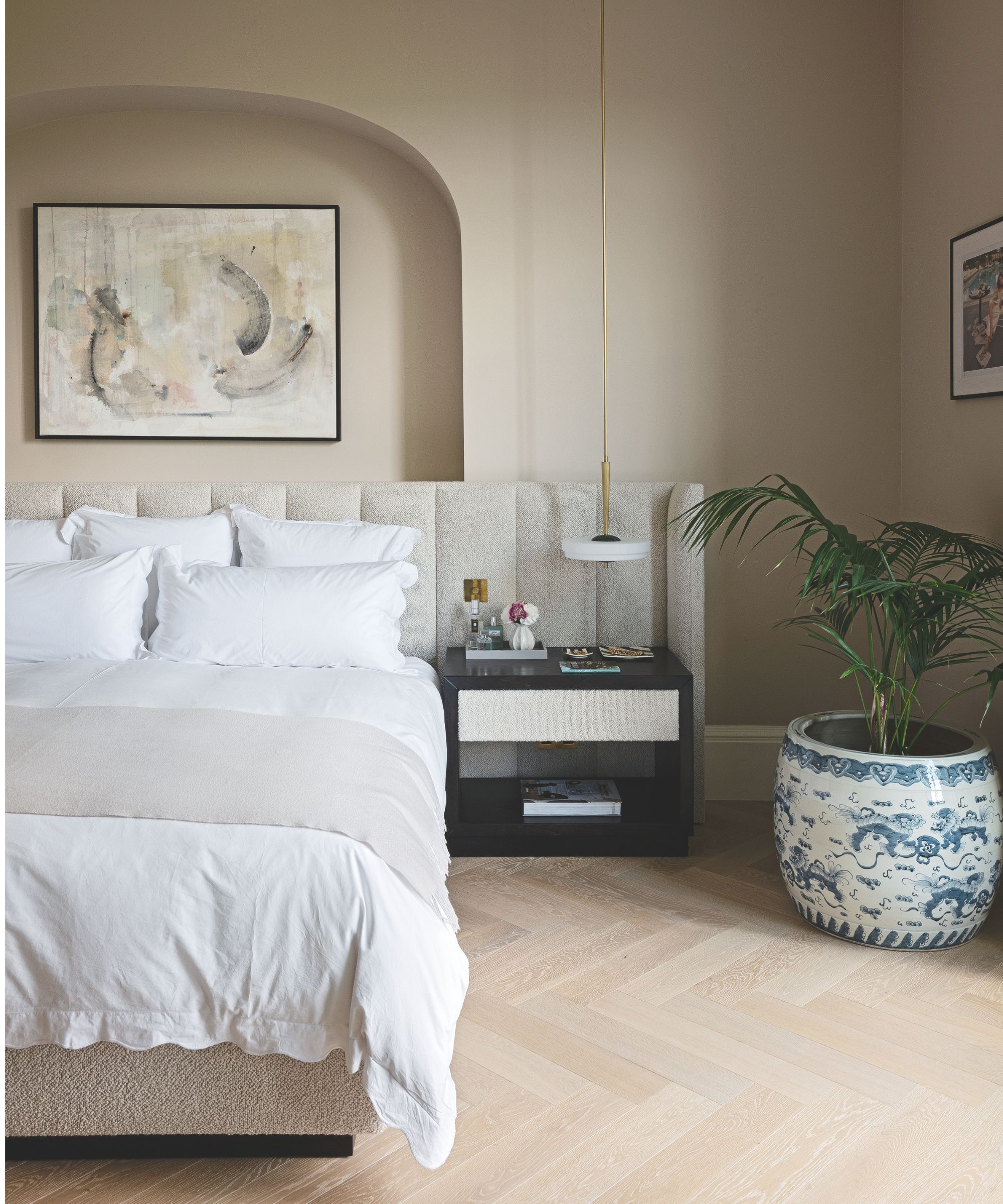 Bedroom with parquet flooring, boucle headboard, and white bedding