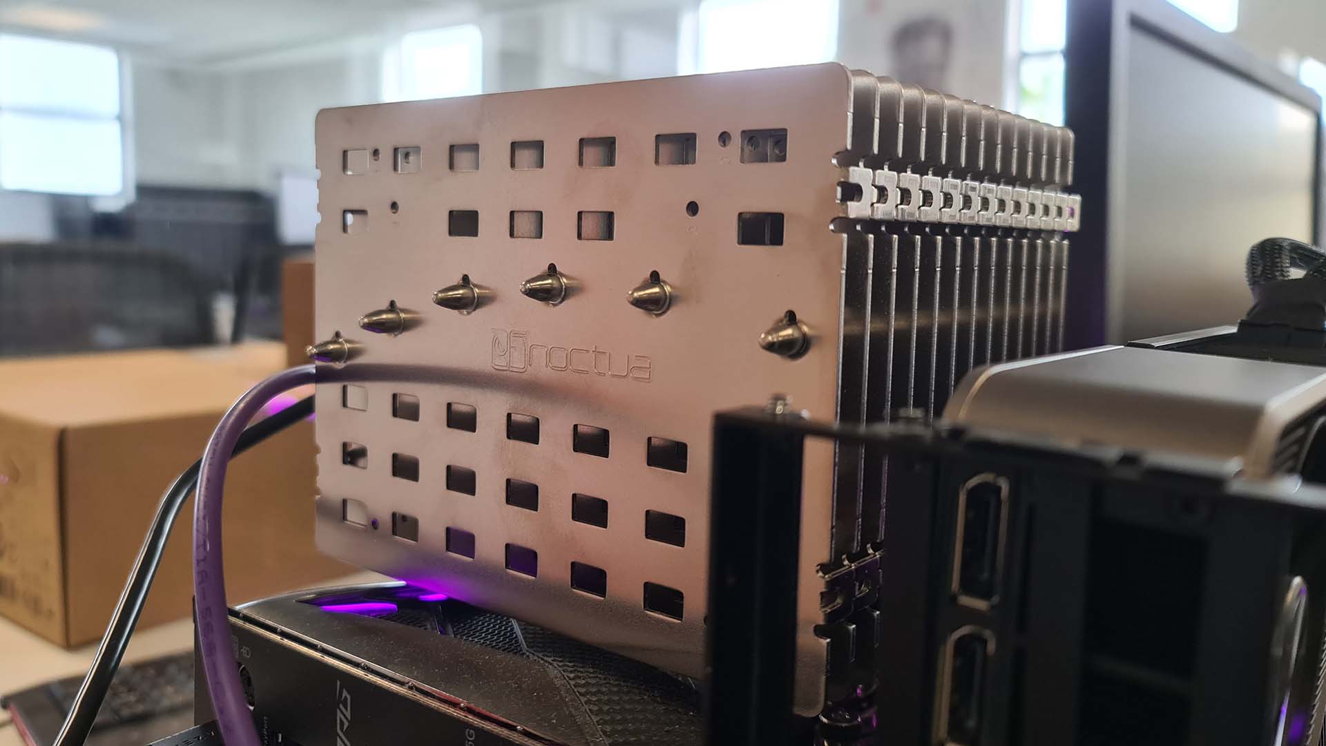 The Noctua NH-P1 air cooler mounted on an open-bed test bench with pink RGB lighting