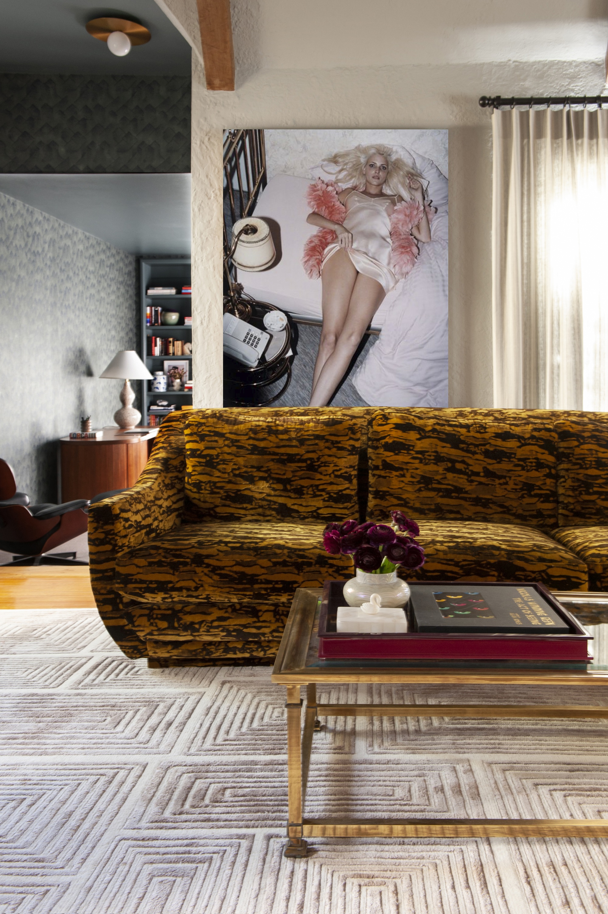 a living room with an abstract tiger print sofa, a gold coffee table, and a large wall art of a woman on a bed