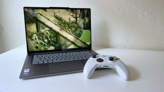 The Lenovo Yoga Slim 7i Aura edition running the game Death's Door on a white table with a white game controller