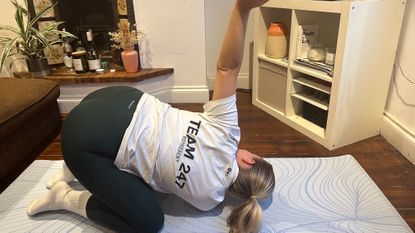 Alice Porter does thread the needle pose at home in living room
