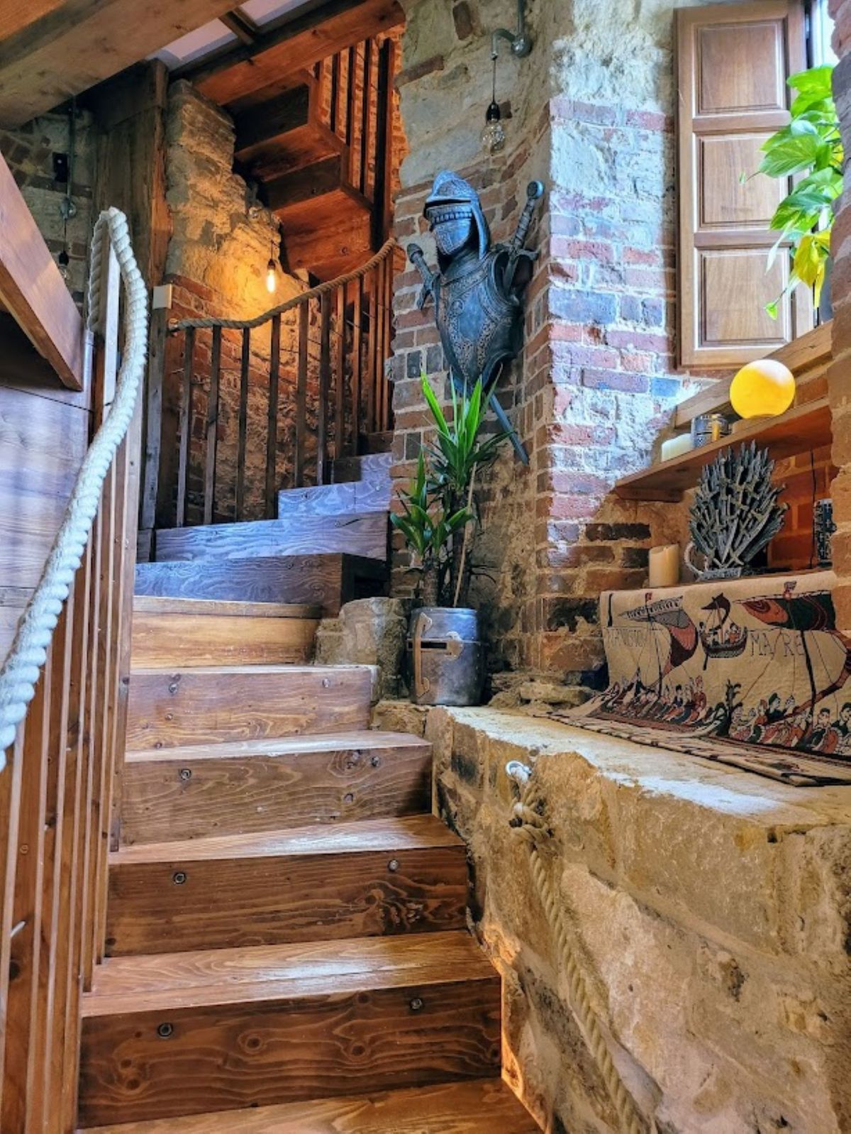 The criss-cross staircase leads to the upper floors and is lit by the window along the wall which is surrounded by the brown brickwork