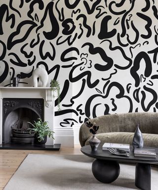 living room with white and black patterned wall, fireplace, gray curved sofa and black coffee table