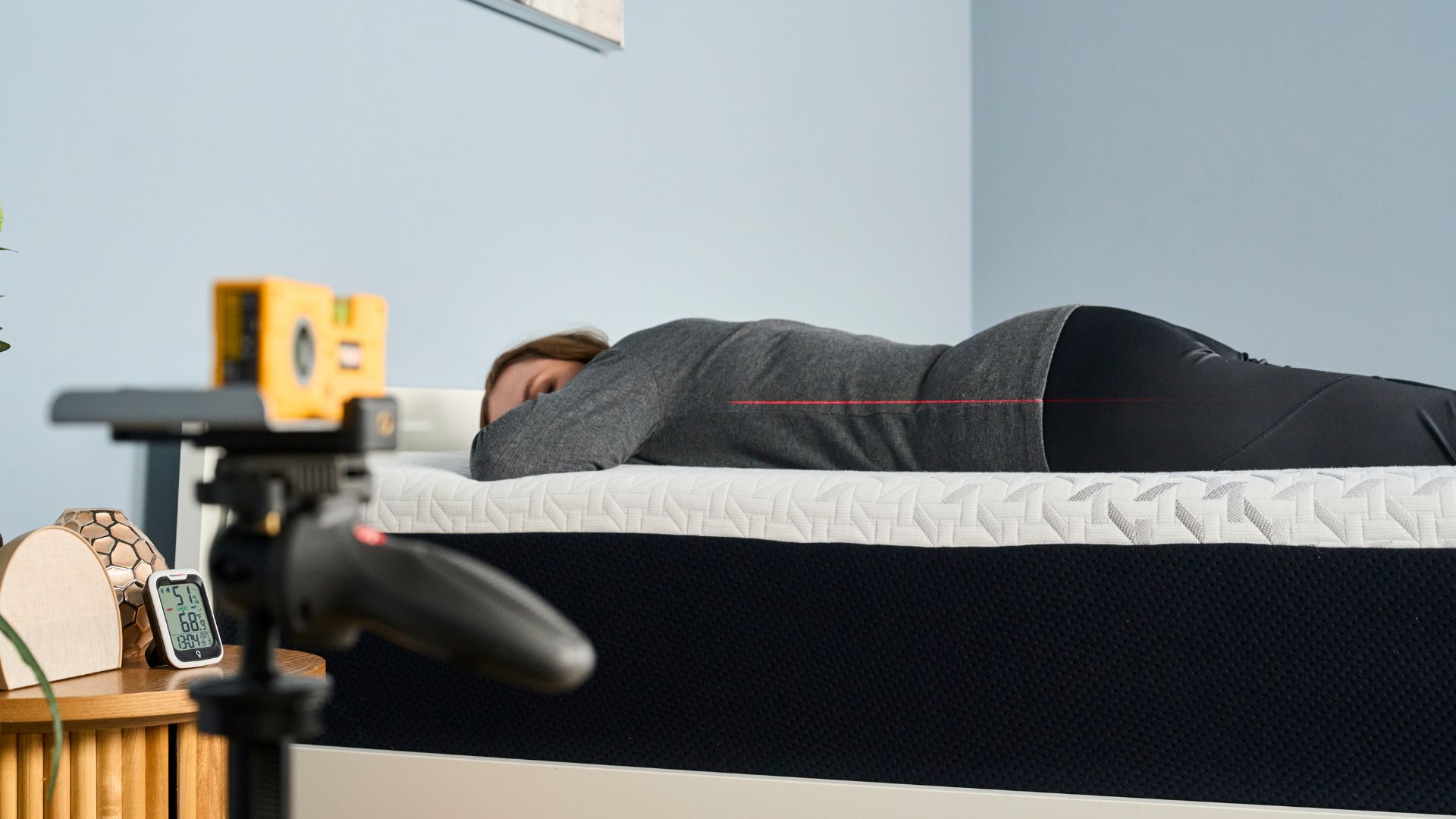 A laser pointer measures how well tester Ruth Jones's spine is aligned when stomach sleeping on the Nectar Premier Memory Foam Mattress.