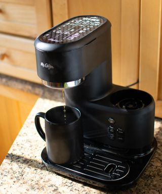 Making a black coffee in a matt black ceramic mug using the Mr. Coffee® Single-Serve Frappe™, Iced, and Hot Coffee Maker and Blender on a granite-effect kitchen worktop
