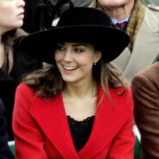 Kate Middleton wears a large black hat and bright red coat and watches Prince William's passing out ceremony at Sandhurst