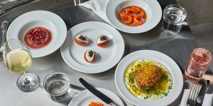 A series of elevated seafood plates in white sits on a chrome-clad table.
