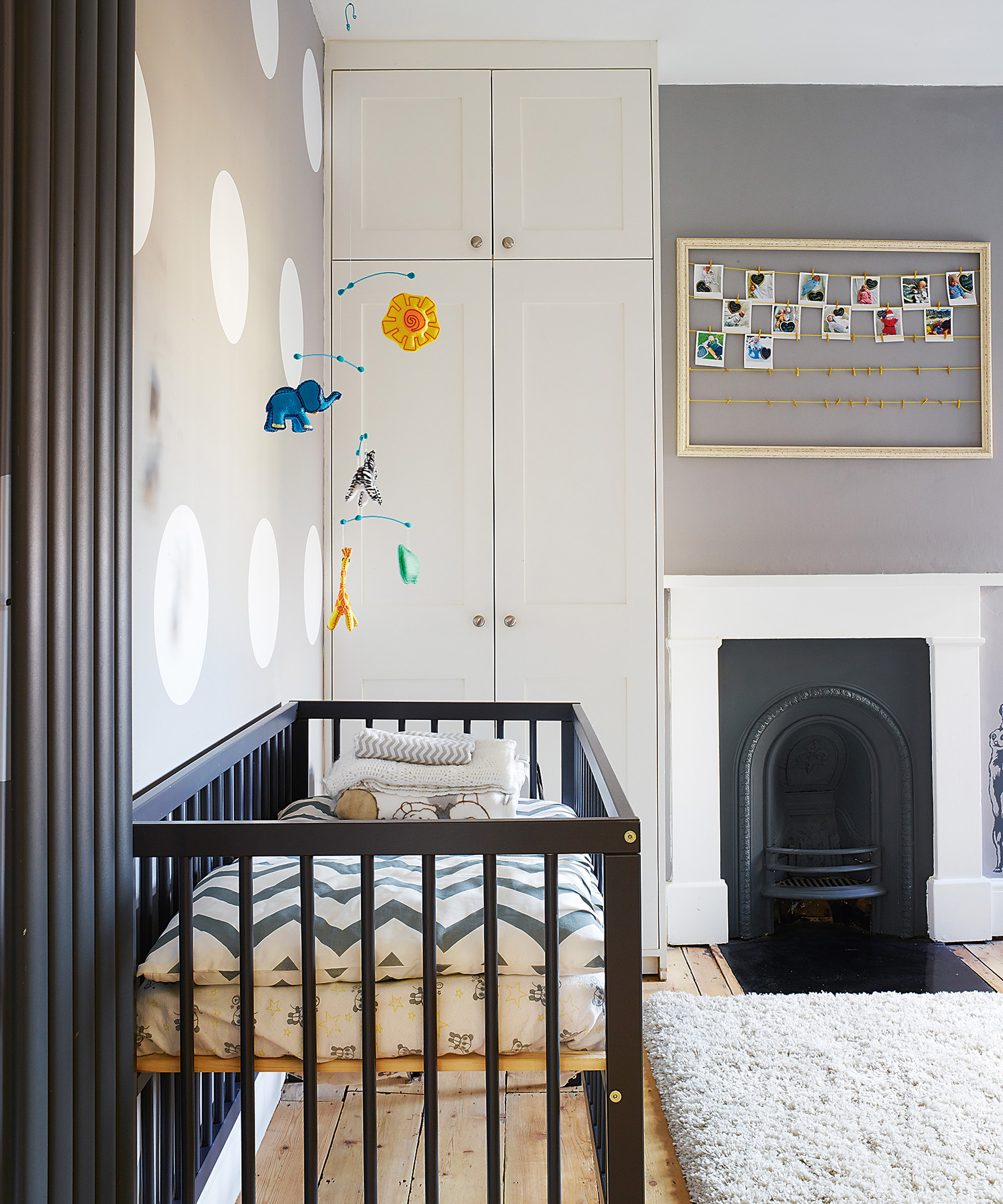 A baby boy nursery idea with black crib and gray wall with white painted polka dots.