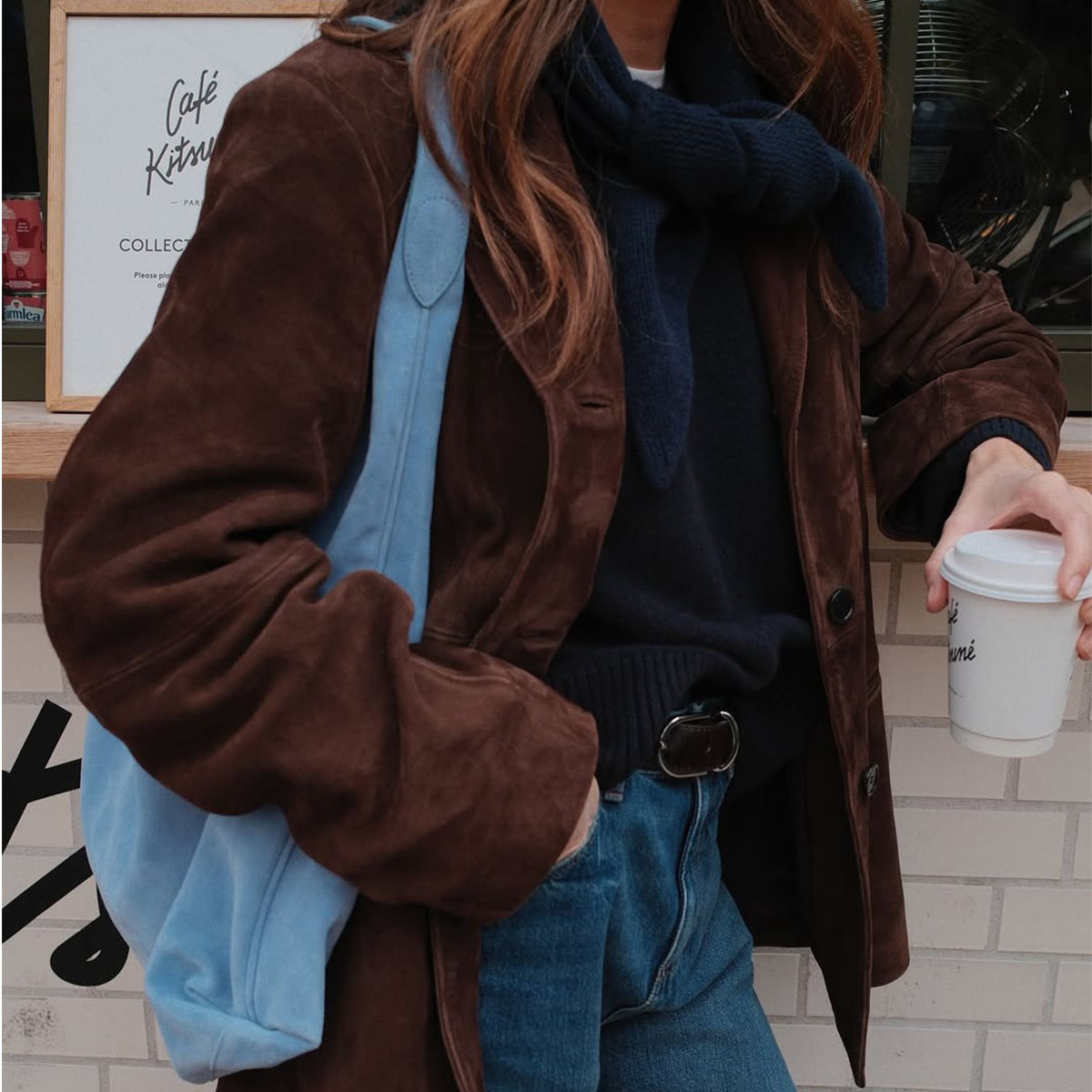 Woman in brown suede blazer and pale blue suede bag