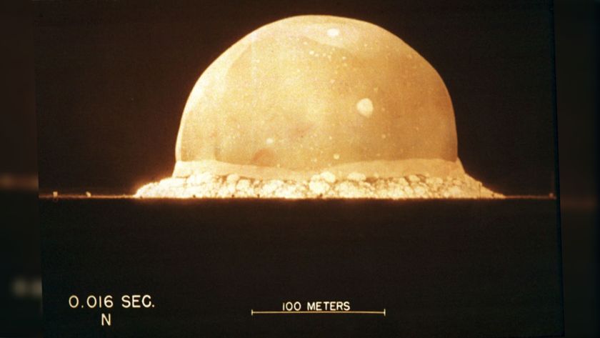 We see an enormous yellow bubble that is an atomic bomb exploding against a black sky.