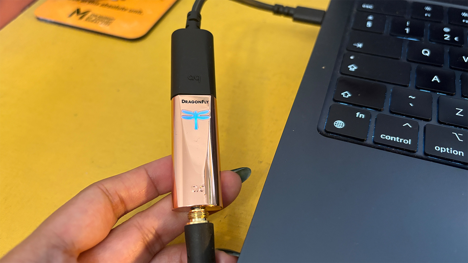 AudioQuest DragonFly Copper DAC connected between headphones and laptop and held in hand