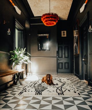 Black hallway with monochrome flooring, orange lamp shade and dog