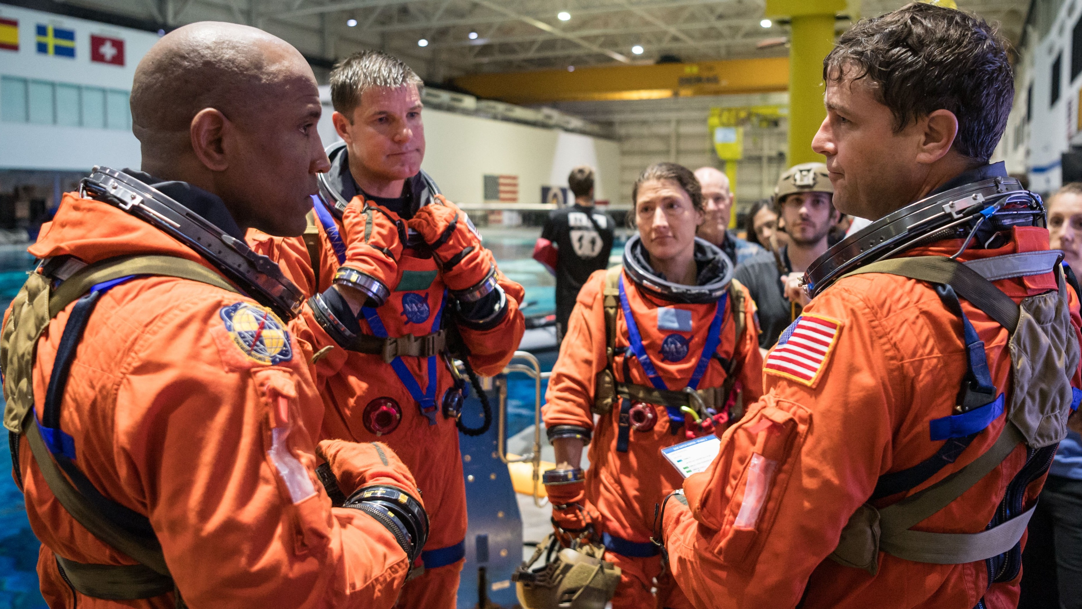 چهار فضانورد با لباس فضایی در دایره ای ایستاده اند و با یکدیگر صحبت می کنند