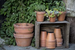 Close up of stacks of terracotta flower pots on a stone floor and wooden box