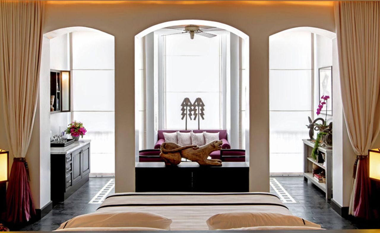 Bedroom featuring archways into a seating area and a statue of a big cat