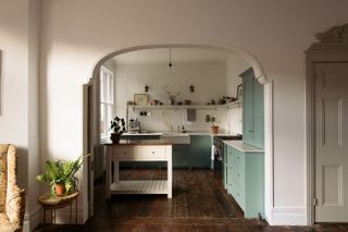 A vintage inspired kitchen with pale green cabinets and a moveable island in the middle of the room