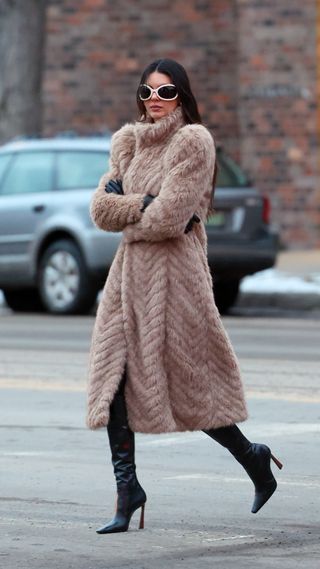 Kendall Jenner wearing a fur coat and a pair of white bug eye sunglasses
