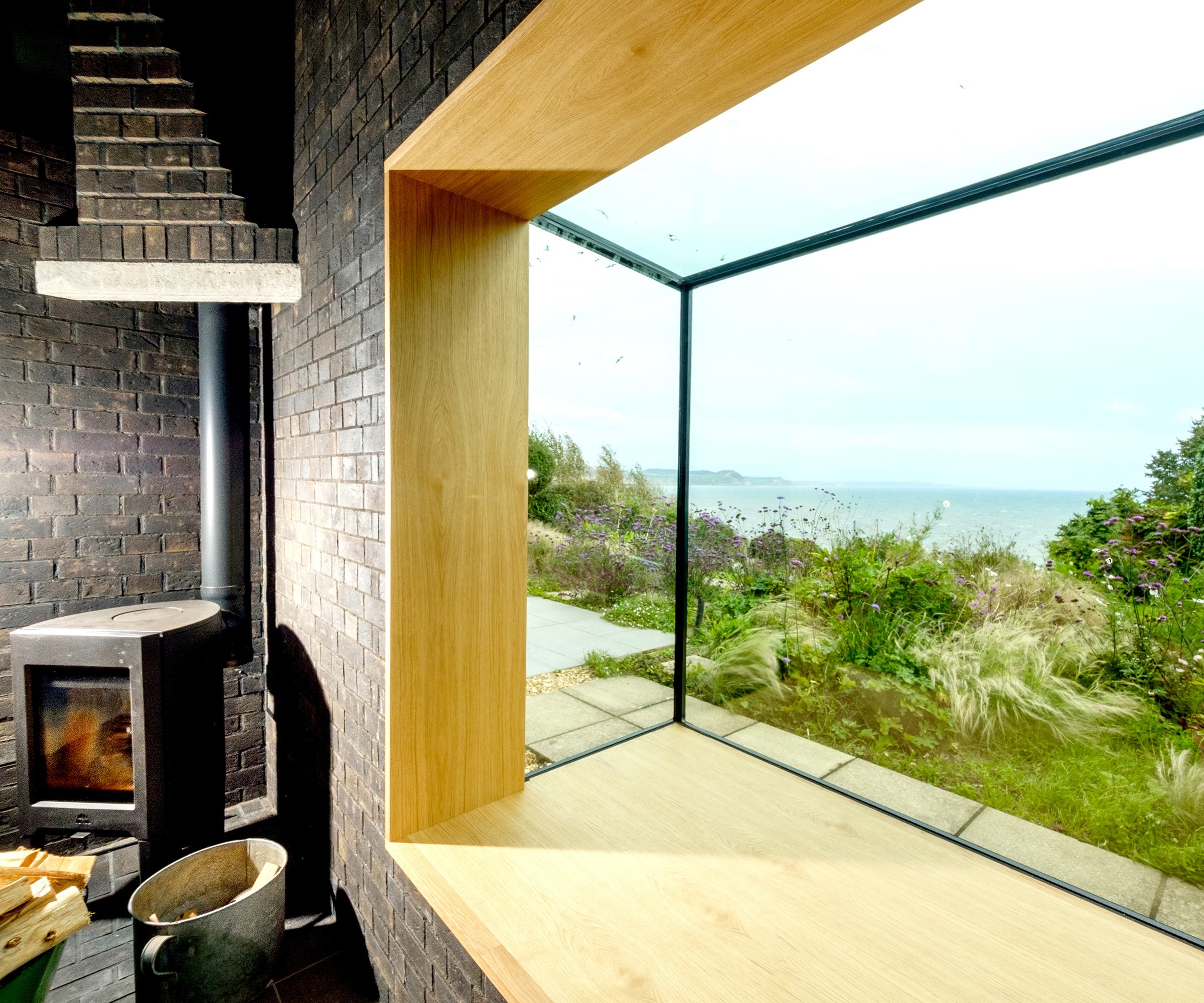 Deep window seat with views out to sea. There is a log burning stove next to it