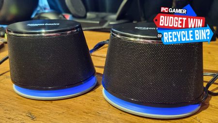 A pair of Amazon Basics Desktop Stereo Speakers on, what else, a desktop, with the RGB lit up in blue and the PC Gamer Budget Win or Recycle Bin badge in the top right
